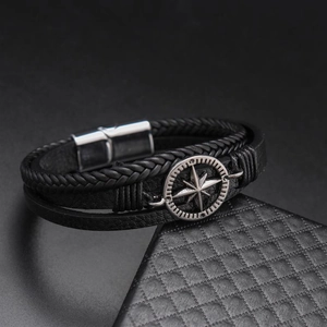 Detail of woven leather bracelet featuring a silver compass star charm and magnetic clasp