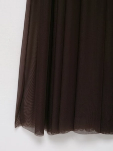 Dettaglio del tessuto in rete marrone scuro con elegante drappeggio per abito midi