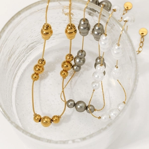 Elegant stainless steel necklace featuring gold beads and white pearls in glass