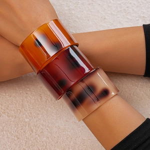 Macro shot of three stacked resin bangles with tortoiseshell amber patterns and glossy finish