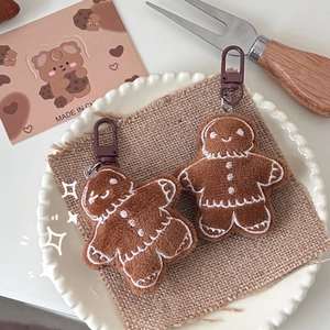 Pair of cute plush gingerbread man keychains on a rustic table setting for Christmas gift