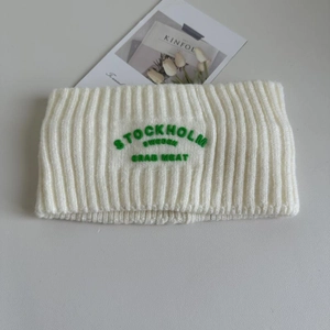 Nahaufnahme des weißen Rippstrick-Stirnbands mit grüner Stockholm Sweden Stickerei