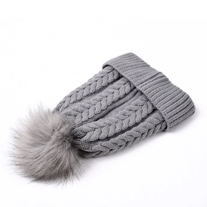 Détail de la maille torsadée et du grand pompon en fourrure sur un bonnet gris foncé