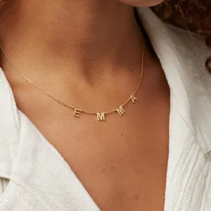 Close-up of golden custom EMMA name necklace worn by a model on a white shirt