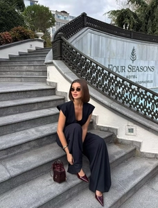 Close-up of stylish pinstripe vest and wide-leg trousers set with a burgundy bucket bag