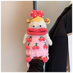 Close-up of a handmade pink crochet doll bag featuring a cherry pattern and pearl necklace