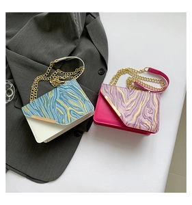 Flat lay of two contrast marble pattern bags with gold chains on a grey suit jacket