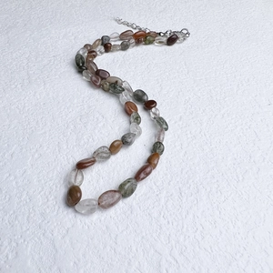 Macro detail of irregular natural crystal beads on a stainless steel necklace chain