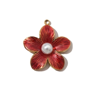 Close-up of a gold-plated flower pendant with red enamel petals and a central white pearl