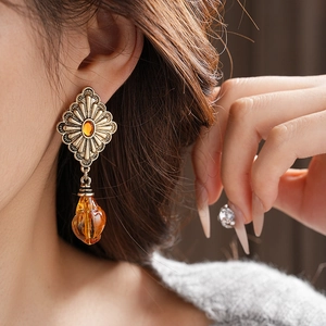 Close-up of vintage gold rhombus earrings with amber gemstones on female model