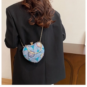 Detail of heart-shaped evening bag featuring blue sequin embroidery and gold chain
