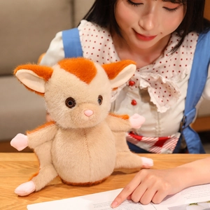 Cute sugar glider plush toy doll in orange and beige on a wooden desk background