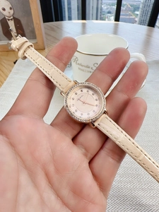 Close-up of rose gold quartz watch with diamond bezel and beige leather crocodile strap