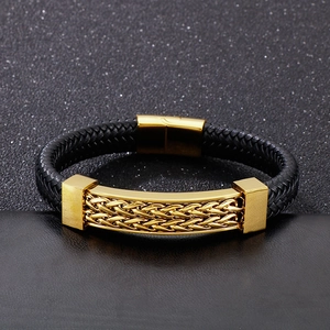 Macro view of men's black braided leather bracelet with golden magnetic clasp and wheat metal plate