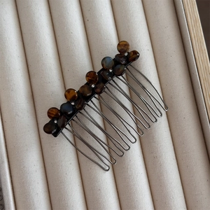 Detail of tortoise shell floral hair comb with rhinestones on a beige tray