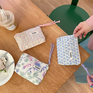 Detailansicht floraler Canvas-Kosmetiktaschen mit gewebten Reißverschlussbändern auf Holztisch