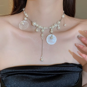 Close-up of pearl and mother-of-pearl shell pendant necklace with silver tassel chains