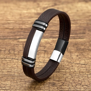 Detail of a brown braided leather bracelet with a silver metal plate and magnetic clasp