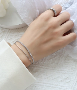 Macro shot of double-layer silver-tone bracelets with cubic zirconia and a textured ring
