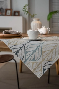 Detail of cotton linen table runner with blue and gold leaf pattern on wooden table