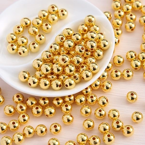 Macro view of gold round acrylic spacer beads in a white bowl for DIY jewelry making