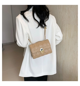 Detailed view of khaki quilted square bag with gold chain strap on a model shoulder