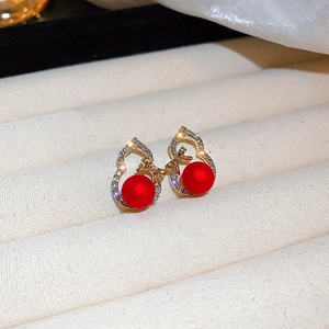 Macro view of gold gourd earrings with red frosted beads and pavé zircon detailing