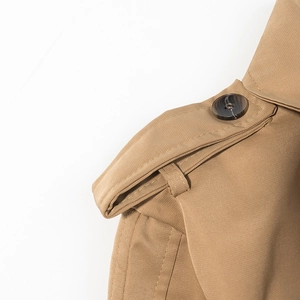 Detail view of khaki trench coat epaulette with fine stitching and textured round button