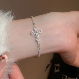 Detail of cross pendant bracelet with pink gemstones and sparkling zircons on wrist