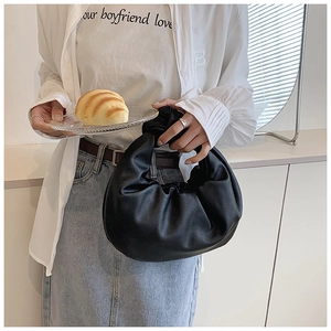 Detail of soft black pleated cloud bag with knotted handle and elegant leather texture