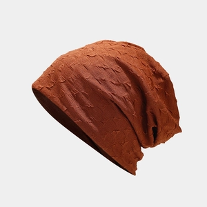 Detailed view of the textured vertical knit fabric on a dark orange slouchy beanie hat
