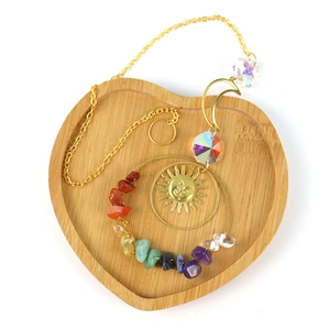 Detailed close-up of crystal suncatcher with colorful crushed stones on heart wooden tray