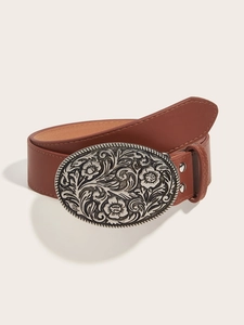 Detail of a brown leather belt featuring a large silver oval buckle with floral relief