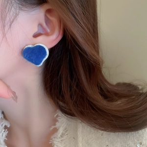Close-up of blue flocked heart stud earring with silver trim worn by a model