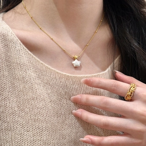 Collier chic plaqué or avec pendentif perle étoile et bague fleur sur modèle