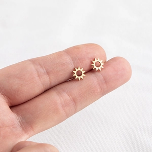 Close-up of gold sunflower stud earrings held by hand to show the actual size and detail