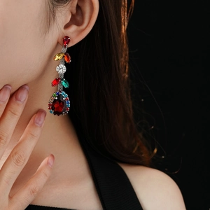 Close-up of vintage earrings featuring red teardrop gemstones and colorful crystals