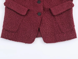 Detailed close-up of wine red boucle wool jacket featuring black buttons and textured fabric