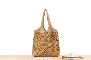 Detailed view of hollow out knit pattern and sturdy handle on khaki paper straw tote bag