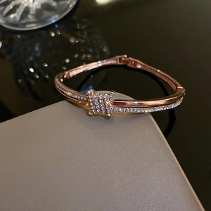 Close-up of rose gold bangle featuring a crystal-encrusted knot on a luxury box