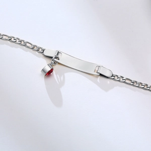 Detail of silver Figaro chain bracelet with a flat rectangular ID plate and red stone