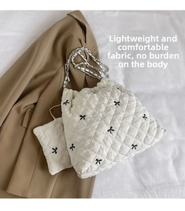 Detail of white quilted bucket bag with bow embroidery and silver chain strap