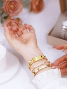 Close-up of a stacked set featuring gold chain ID bracelet and gemstone bangles for women