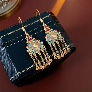 Détail de boucles d'oreilles cœur en or 18K avec motif de poisson en émail et longs glands