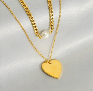 Close-up of double-layer necklace with gold heart pendant and white round pearl detail