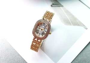 Gros plan d'un cadran de montre ovale doré avec chiffres romains et lunette en diamant