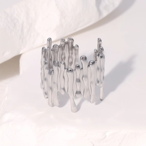 Vue détaillée d'une bague en argent liquide sur un fond de pierre blanche texturée