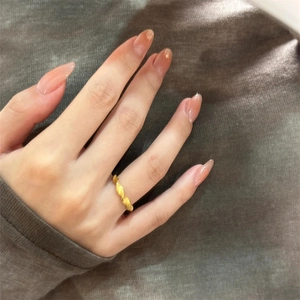 Close-up of gold-plated twisted ring on hand with light pink manicured nails