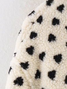 Close-up texture of cream fleece jacket with black heart print and soft plush finish