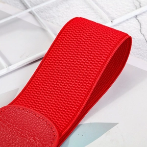 Detailed macro view of red elastic fabric belt texture and circular faux leather buckle